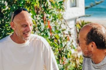 A photo of a female audiologist providing a hearing aid consultation to a middle-aged male client with brown skin and a beard.