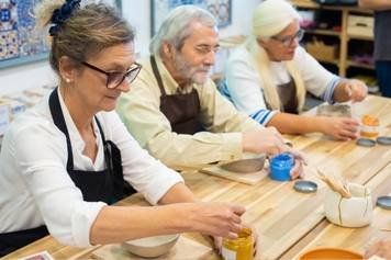 A photo of a male hearing instrument specialist repairing a pair of hearing aids.