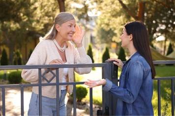 A photo of a female audiologist providing a hearing aid consultation to a middle-aged male client with brown skin and a beard.